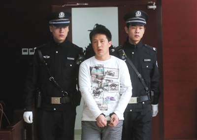 昨日，被告人李某被法警带进法庭受审。