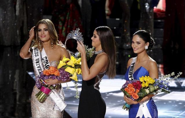 20日，上届“环姐”、来自哥伦比亚的保利娜·维加（中）正为真正的2015年环球小姐、菲律宾佳丽武茨巴赫（右）佩戴桂冠。此前，因主持人口误，保利娜一度将桂冠戴在了“老乡”阿里亚德娜·古铁雷斯（左）头上。