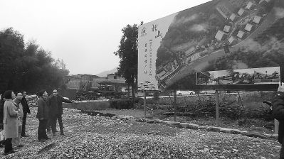 北山村的发展受到社会各界关注，图为李立光（右一）在向来客介绍畲族风情广场规划