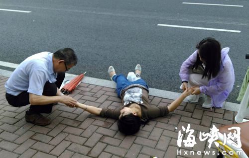 两热心市民正在给晕倒女子摁虎口（读者供图）