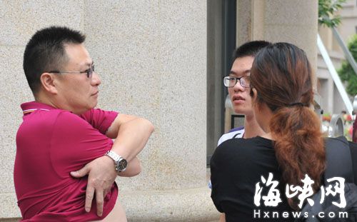 屏东中学外，因带金属的衣服不能通过检查,父亲赶快和儿子换衣服，妈妈帮儿子穿上