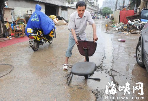 福州秀坂路大坑多且积水 热心男子摆椅子提醒