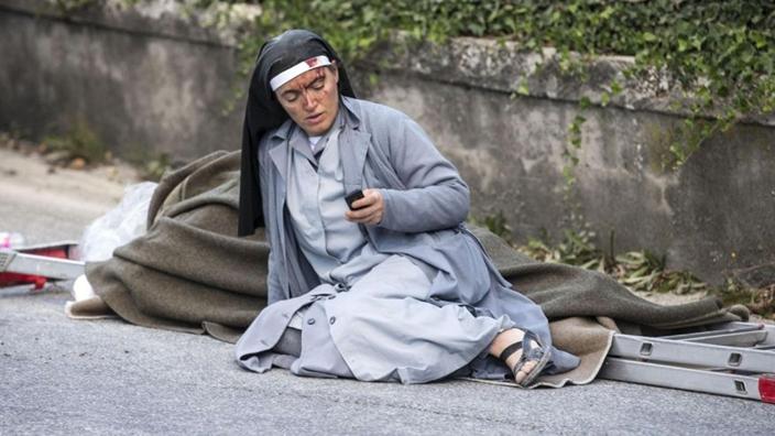 修女瘫坐路边报平安成意大利巨震劫后余生的象徵