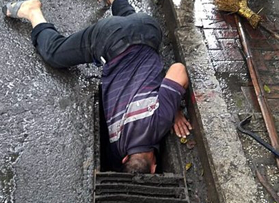 防止路面积水 环卫工雨中“埋头”疏通下水道
