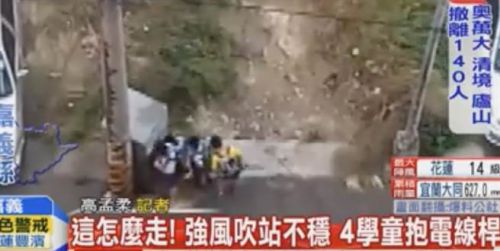 嘉义县小学生不敌强风吹袭，只能躲在电线杆后方。（图片取自台湾中天新闻）