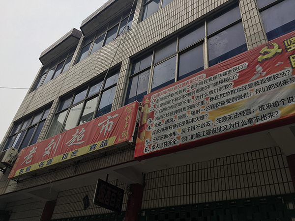 老刘超市的招牌旁，挂着老刘家制作的“五问轨道公司”的字牌。