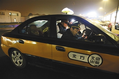 昨日晚上11点10分，首都机场T2航站楼，一名涉嫌私改计价器的出租车司机，被执法人员查获后，坐在后座上等候处理。本版摄影/新京报记者 大路