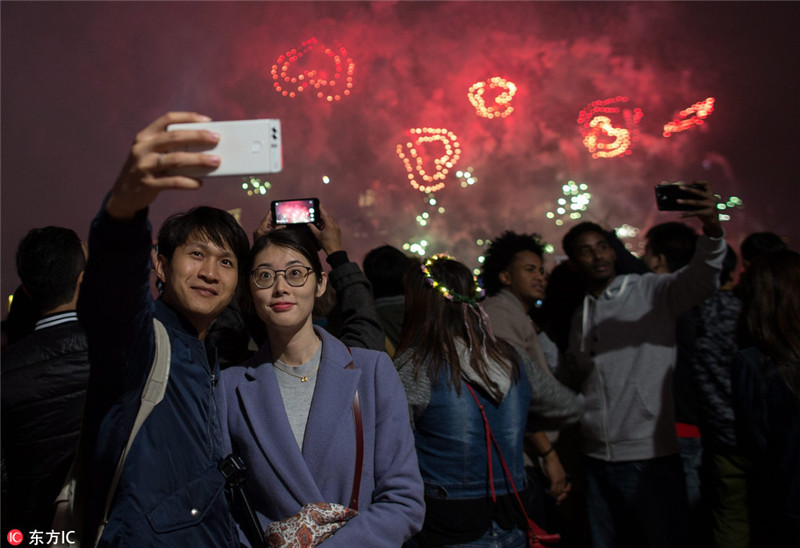 2017年1月1日，中国香港，一年一度跨年烟花汇演在香港维多利亚上空举行，火树银花不夜天，喜迎2017新年到来。 香港会展中心打出2017字样，迎接新年。 一对情侣对着手机，自拍留影。