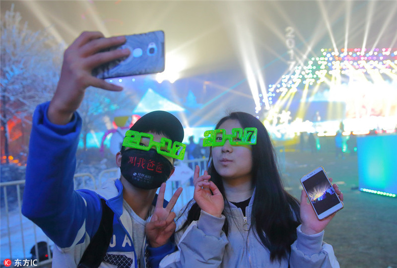 中国日报网2017年1月1日电2016年12月31日，北京奥林匹克森林公园，2017北京新年倒计时活动暨首届北京冰雪文化旅游节开幕式结束后，现场观众戴着2017字样的眼镜照相留念。