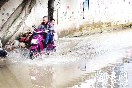 琴亭小学门前积水，骑车接送的家长只能涉水而行