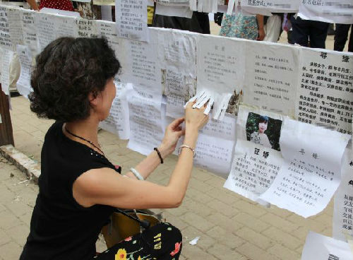 在武汉市中山公园内，一位母亲在张贴女儿的基本信息。 新华社发